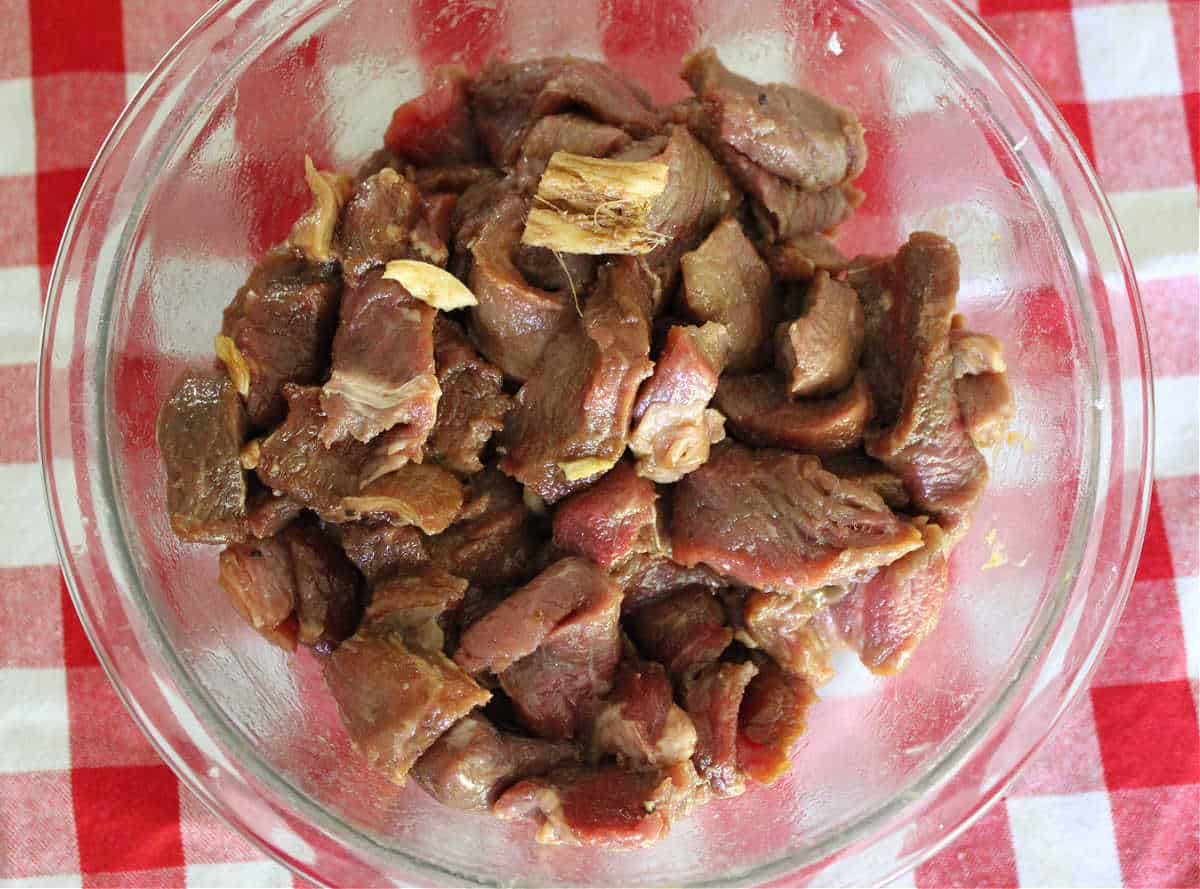 thinly sliced beef marinating in a glass bowl
