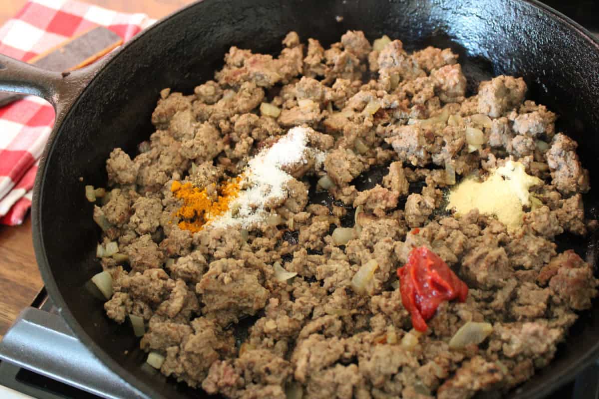 seasonings and tomato paste on the browned ground beef
