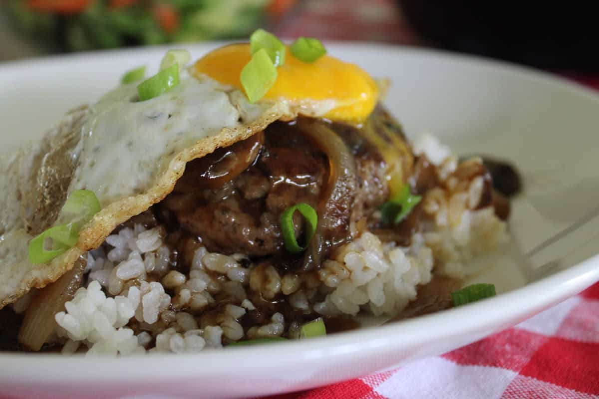 close up of loco moco on white rice with a sunny side up egg