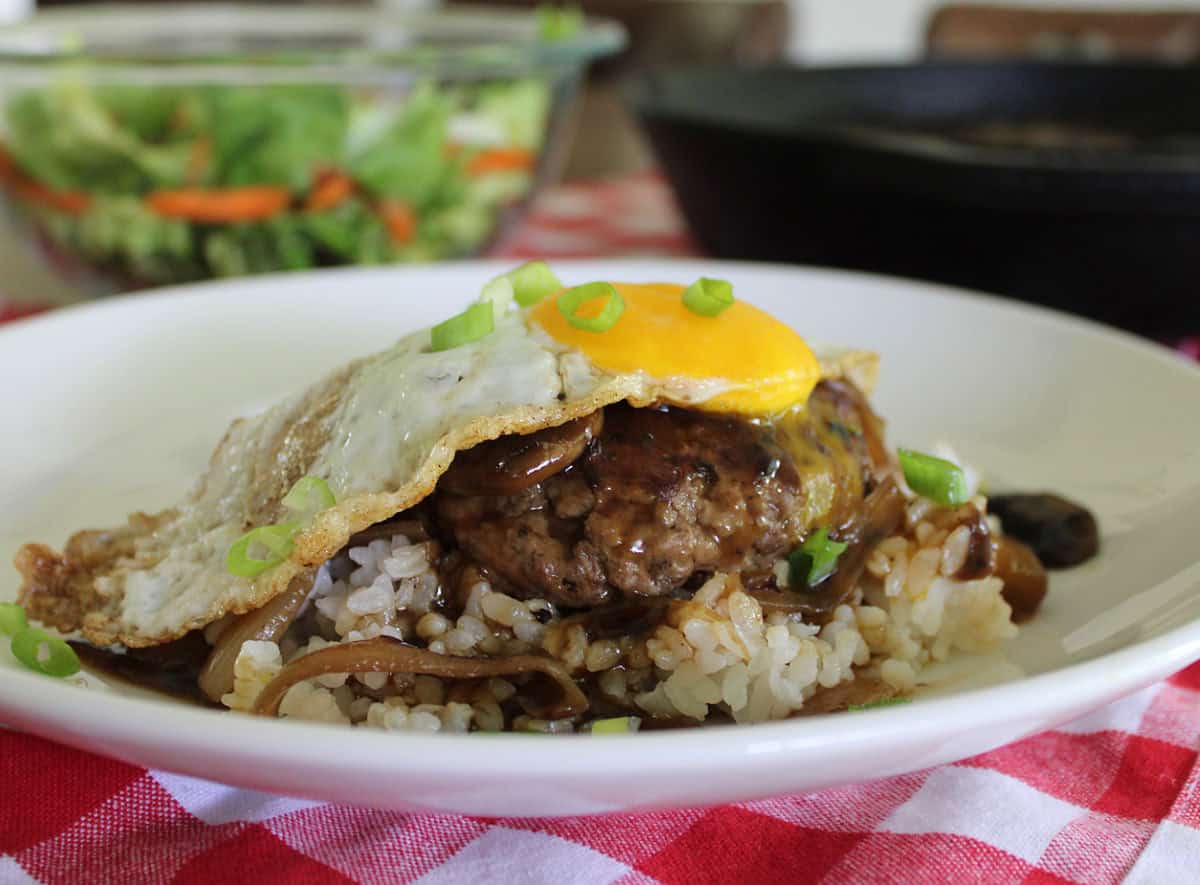 loco moco on white rice garnished with sliced green onions