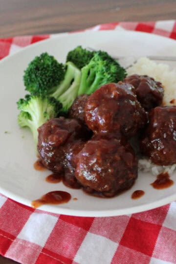 sweet and sour meatballs on a white plate served with rice and broccoli