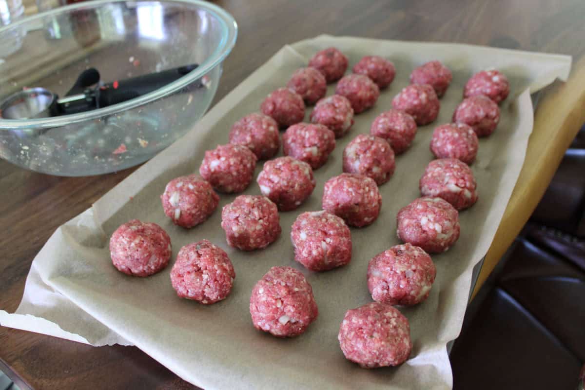 raw meatballs on parchment paper lined cookie sheet