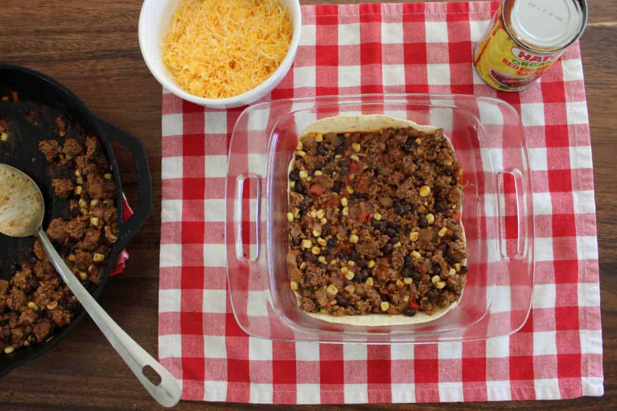 ground beef mixture being layered into the casserole