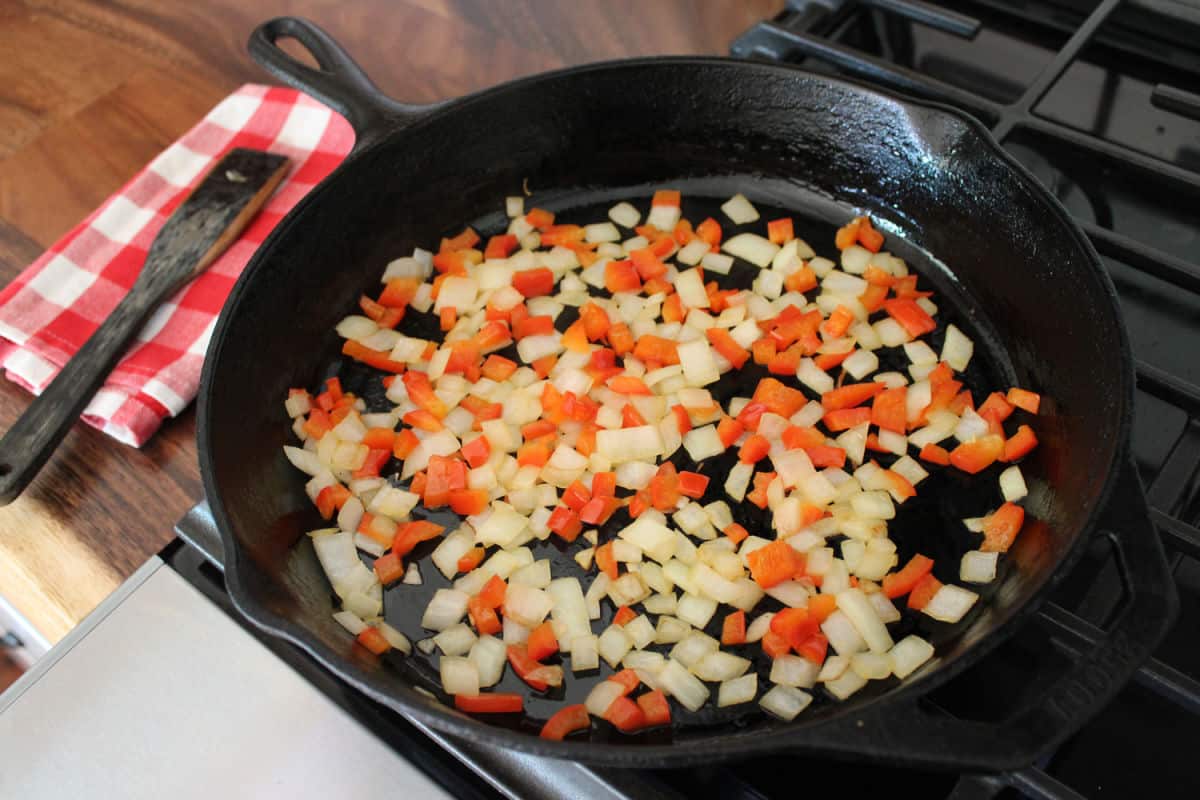 onion and red bell pepper cooking a large cast iron skillet