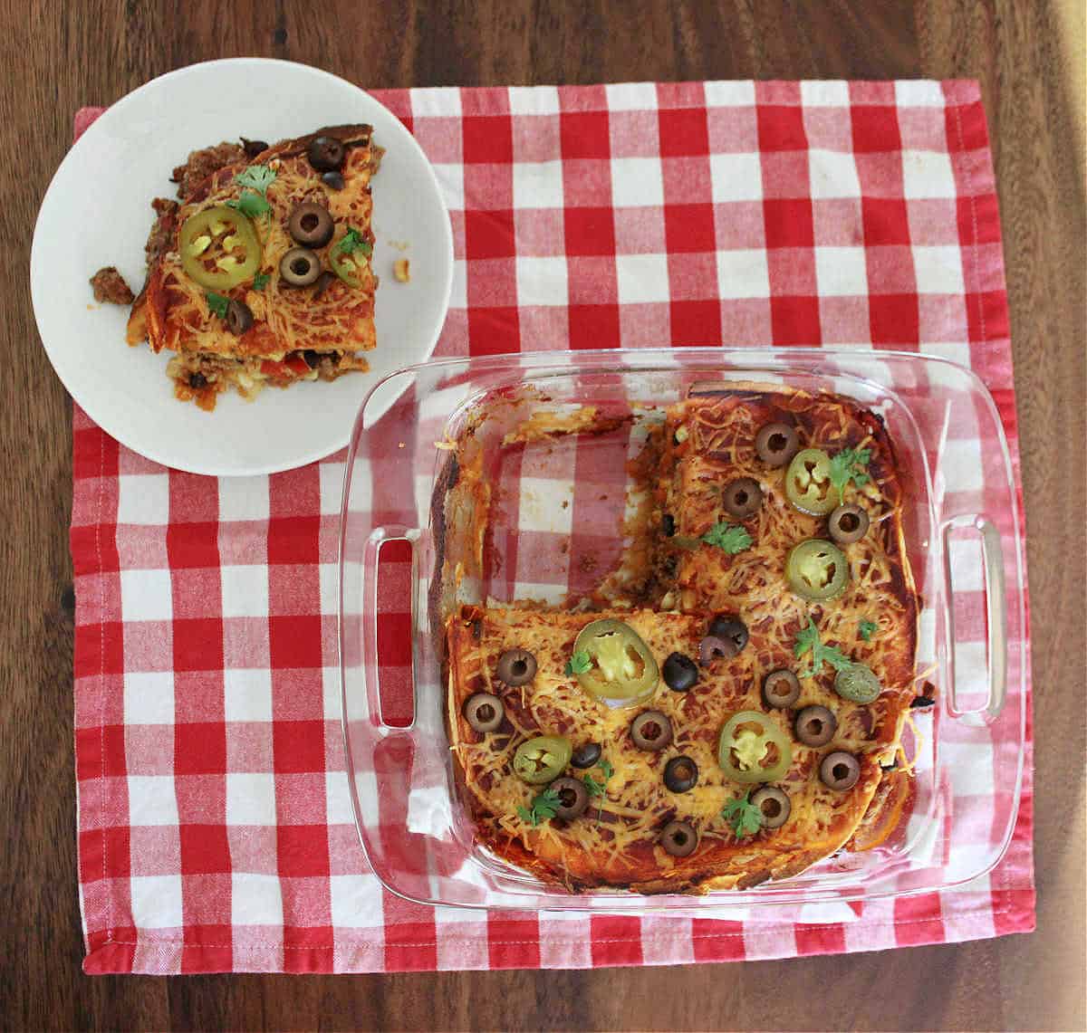 9 by 9 baking dish with a slice of the beef enchilada casserole missing