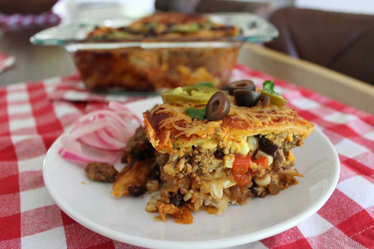 enchilada casserole served on a white plate with a side of pickled onions