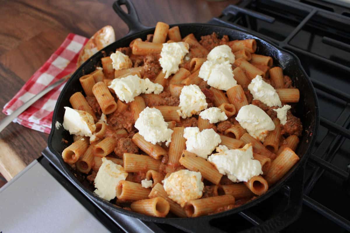 dollops of ricotta on rigatoni in a cast iron skillet