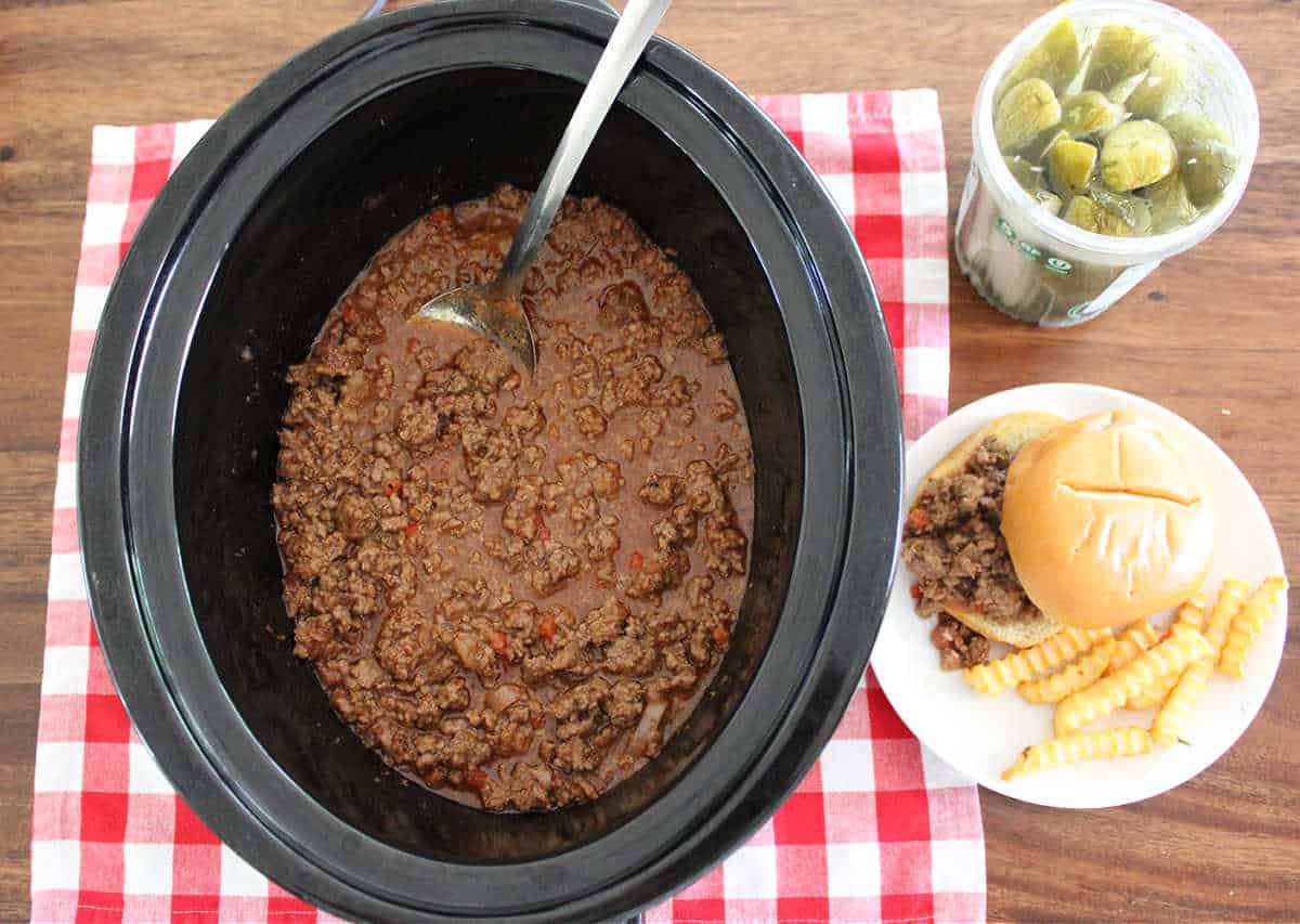 slow cooker sloppy joe mixture with a side of pickles and french fries