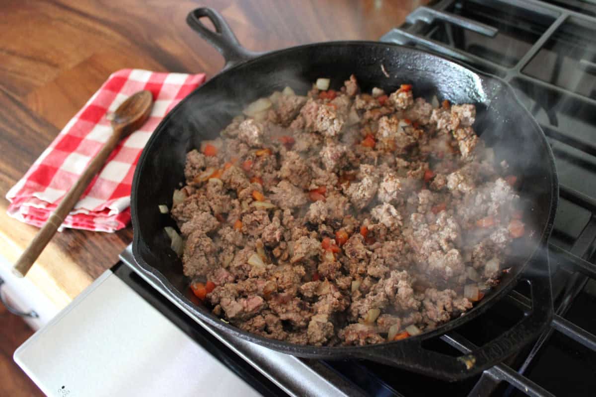 browned ground beef with onions in a black cast iron skillet