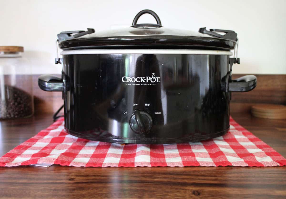 Black Slow Cooker on a wooden counter top.