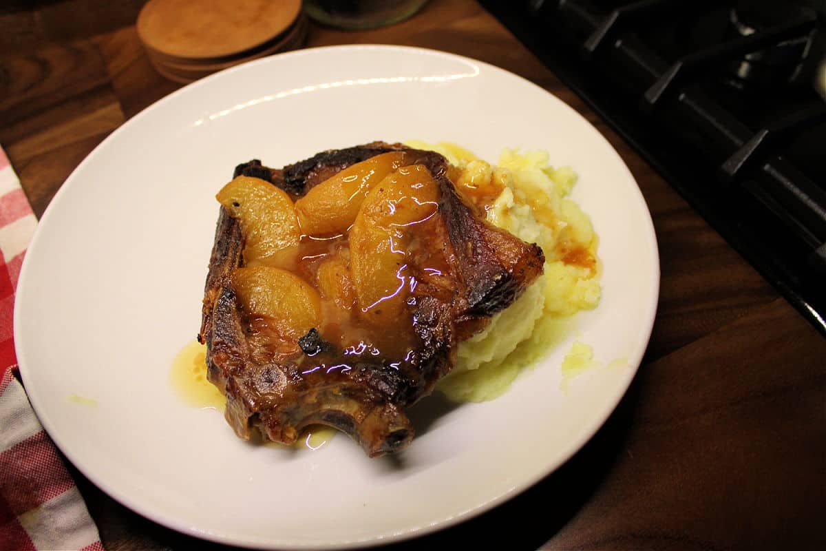 Cooked pork chops and peaches served over mashed potatoes.