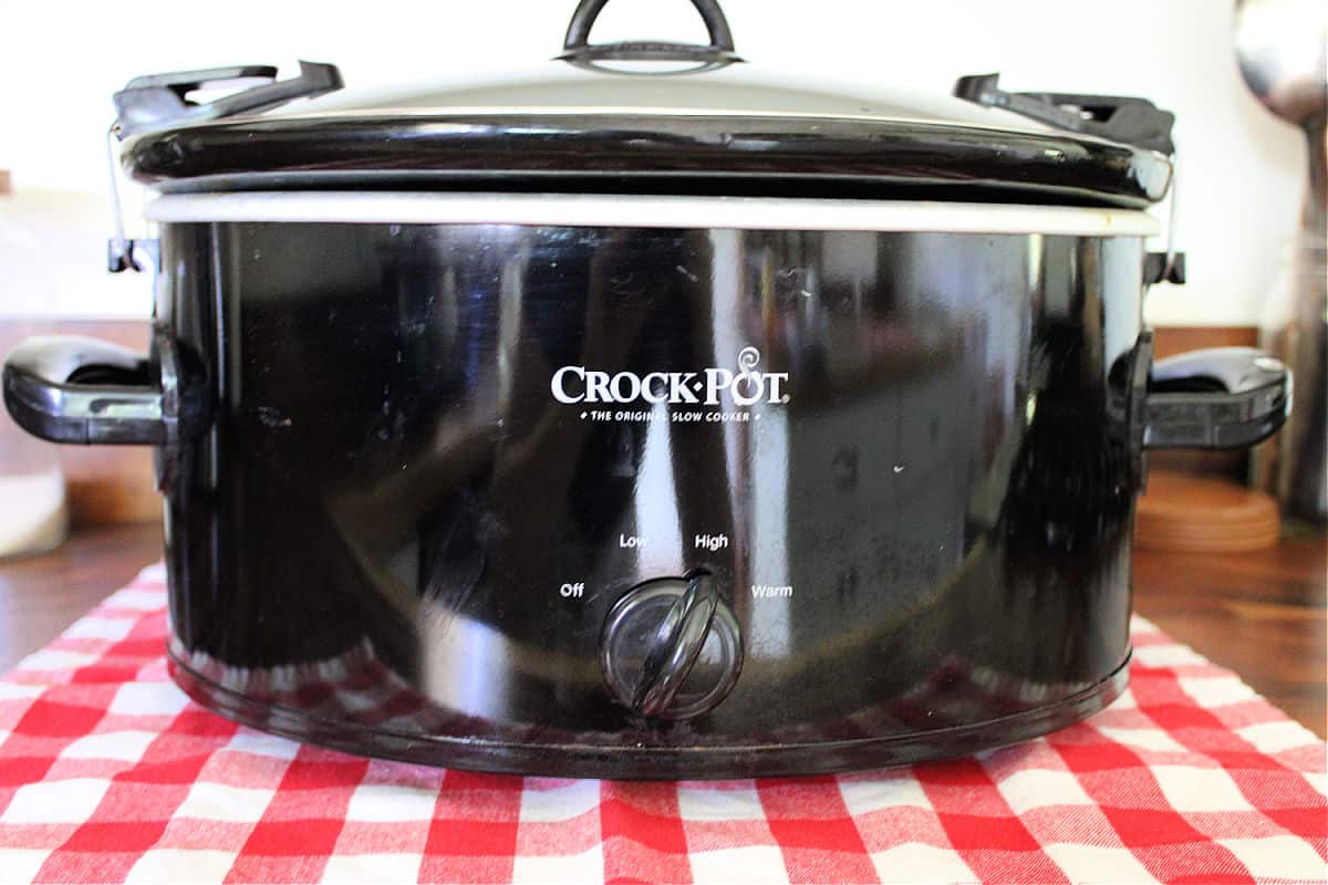Black crock pot on a wood counter top.