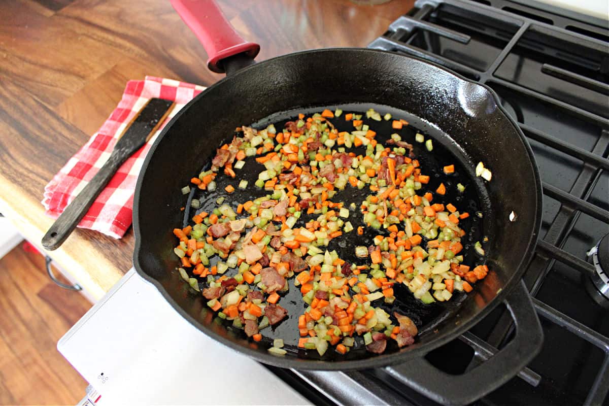 finely minced vegetables being sauteed in a black cast iron skillet