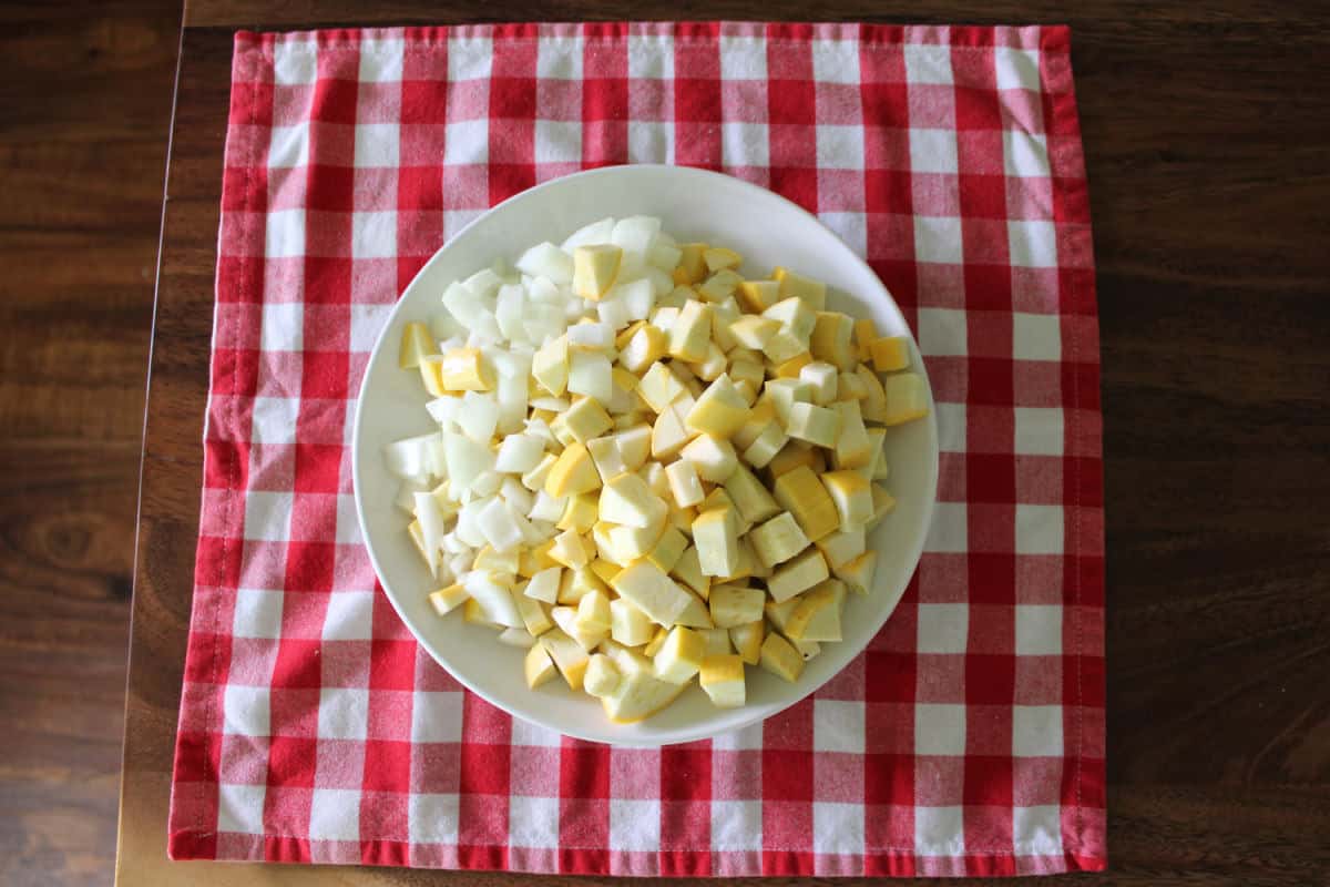 diced yellow squash and yellow onion on a white plate
